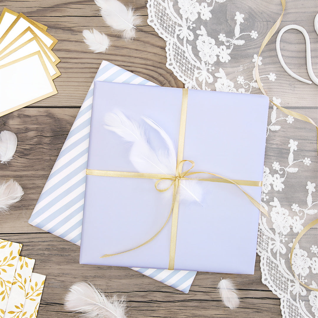 Geschenkverpackungen mit einem eleganten lila Geschenkpapier und einer Feder, dekoriert mit goldenem Band.